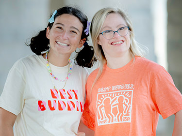 Male buddy pair sitting on stairs with arms over one another's shoulders