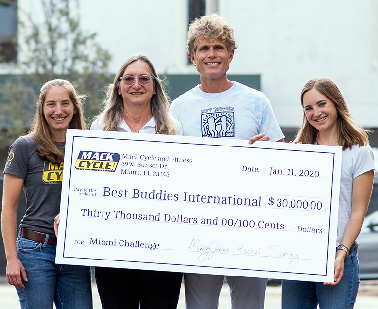 Mack Cycle & Fitness Donates $30,000 to Best Buddies International in Support of Individuals with Intellectual and Developmental Disabilities Anthony Shriver, Founder of Best Buddies International, holds a large presentation check for $30,000 dollars. The owner and her two daughters are standing next to him.
