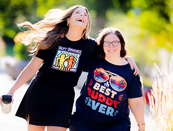 Two male Best Buddies participants walking together with smiles on their faces
